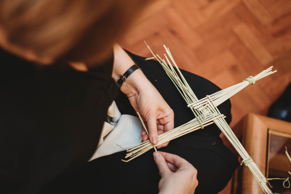 Woman's hands making a St Brigid's Cross from rushes
