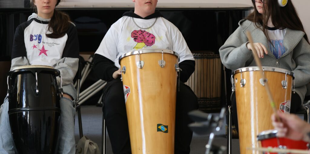 3 children playing bongo style drums.